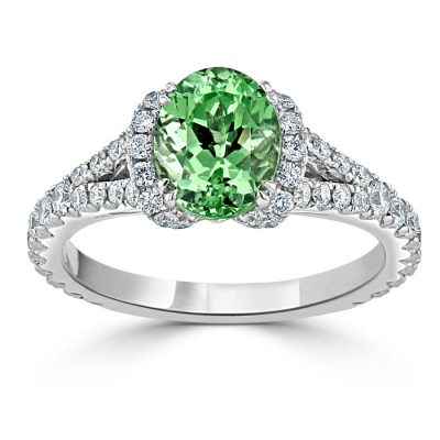 A green garnet stone surrounded by small diamonds set into a platinum ring.